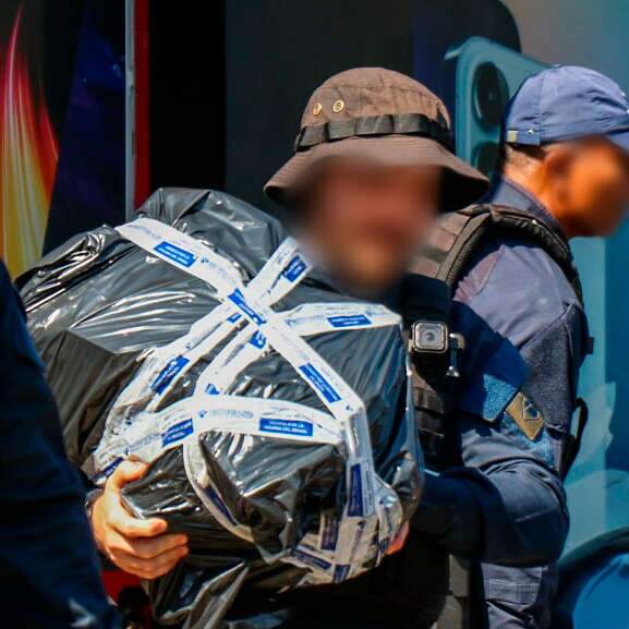 Policial saindo com pacote de produtos apreendidos (Foto: Henrique Kawaminami)