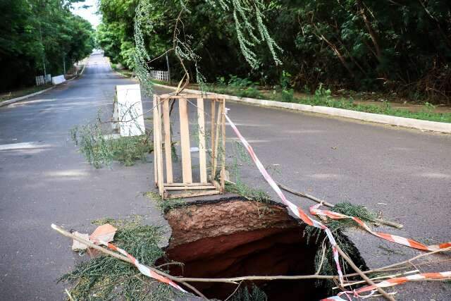 Asfalto cede e cratera interdita trecho da Rua Sagarana, às margens de córrego