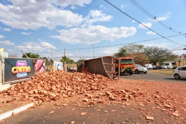 Caminh&atilde;o com tijolos tomba em rotat&oacute;ria e motorista fica preso &agrave;s ferragens