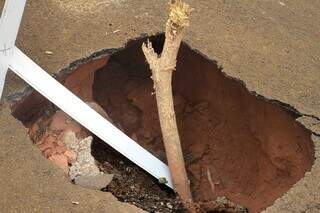 Moradores improvisam cruz para sinalizar buraco em rua do Jardim Centenário Moradores improvisam cruz para sinalizar buraco em rua do Jardim Centenário