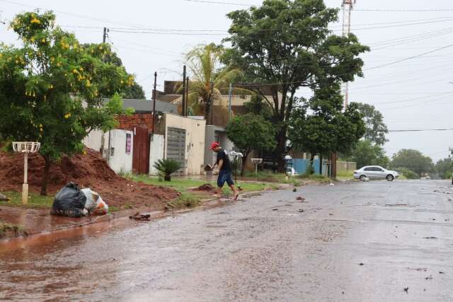 Morador limpa boca de lobo com enxada para evitar alagamento de casa