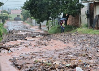 Morador limpa boca de lobo com enxada para evitar alagamento de casa