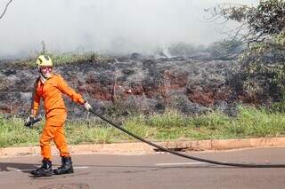 Bombeiros combatem fogo em terreno em frente a condom&iacute;nio no Veraneio