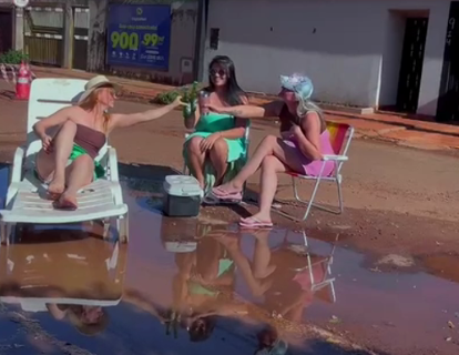 Amigas simulam praia em protesto contra buracos em rua