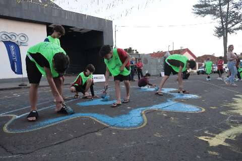 Alunos de escolinha de futebol ajudam a pintar rua da Cidade da Copa