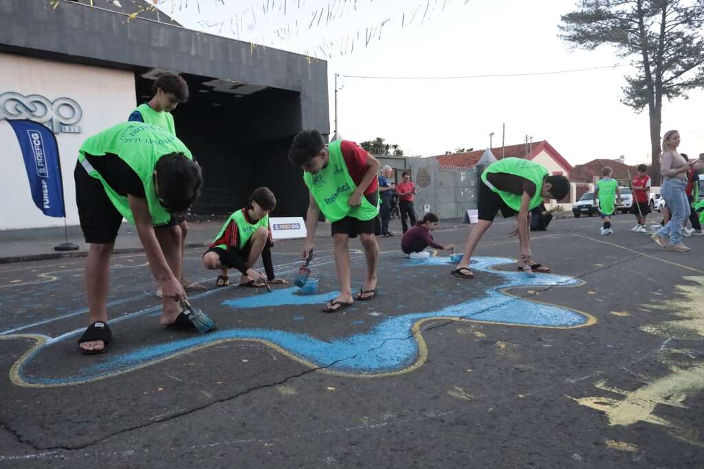 Alunos de escolinha de futebol ajudam a pintar rua da Cidade da Copa