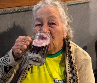 Com 83 anos, Maria foi para o bar ver jogo do Brasil tomando uma gelada no frio