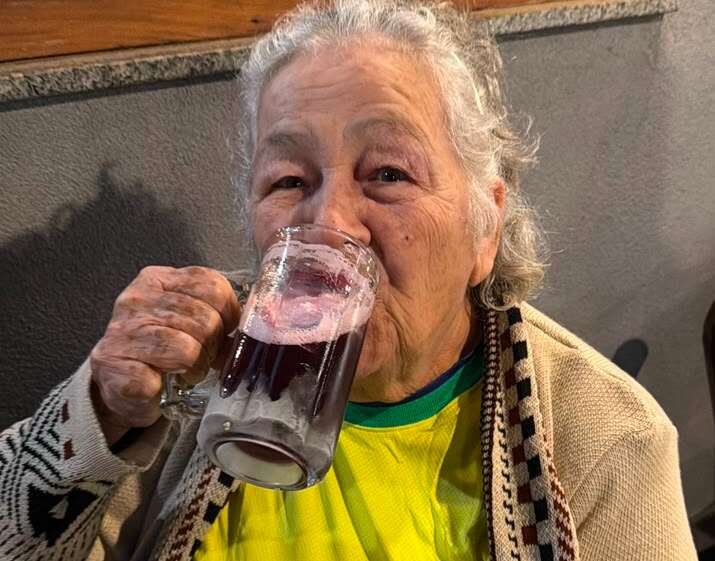 Com 83 anos, Maria foi para o bar ver jogo do Brasil tomando uma gelada no frio