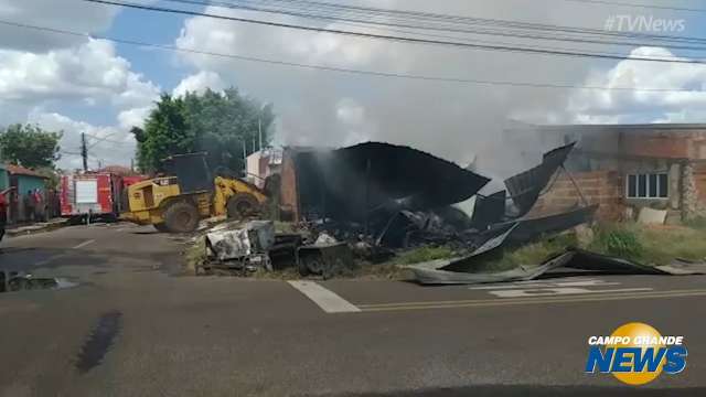 Retroescavadeira faz retirada de materiais em depósito atingido por incêndio