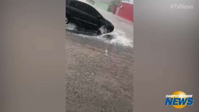 Chuva alaga avenida e comerciante usa rodo para evitar que água entre em loja