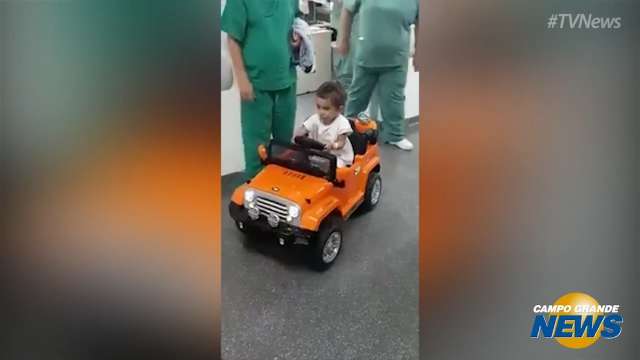 Criança indo no carrinho de controle remoto para sala de cirurgia