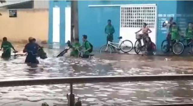 Moradores atravessando ruas alagadas em Três Lagoas