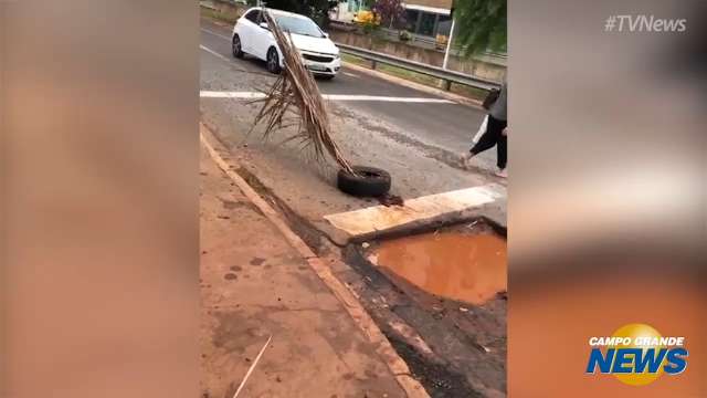 Para evitar acidentes, comerciante sinaliza buraco com pneu na Ernesto Geisel