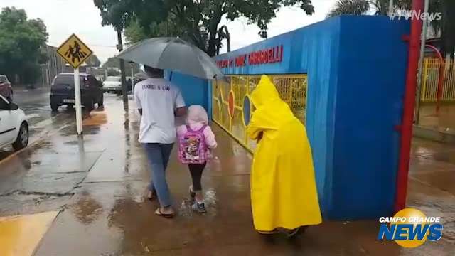 Na frente das escolas, guarda-chuva foi item obrigatório para mães e filhos