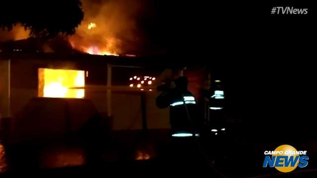 Bombeiros tentam conter as chamas na residência, que ficou destruída