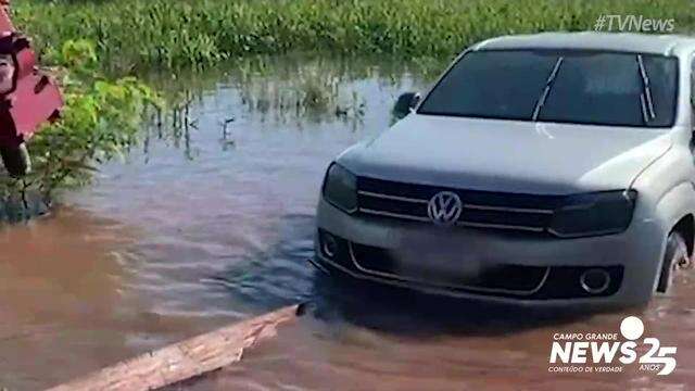 Trator tirando caminhonete sobre o Rio Negro, na Estrada Parque